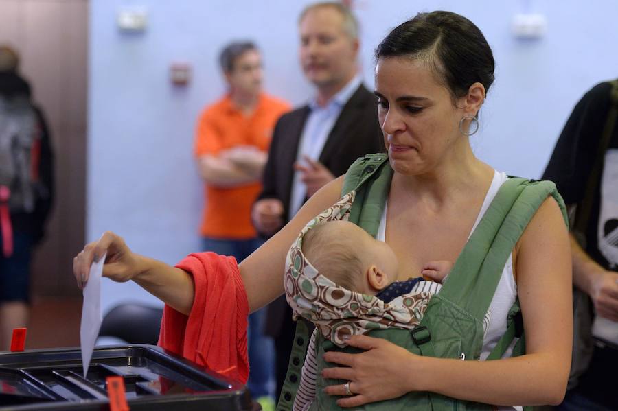 Una mujer junto a su bebé deposita su voto.