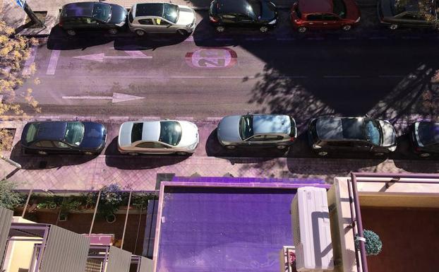 Vista cenital de la calle con las aceras, el asfalto, las terrazas y balcones cubiertos de polvo de color morado.