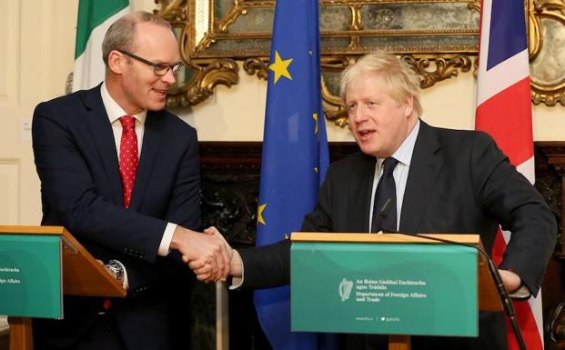 Coveney (i) esstrecha la mano de Boris Johnson. 