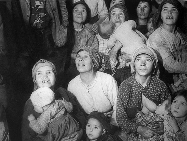 Mujeres y niños viendo una sesión de cine en una fotografía de Val del Omar.