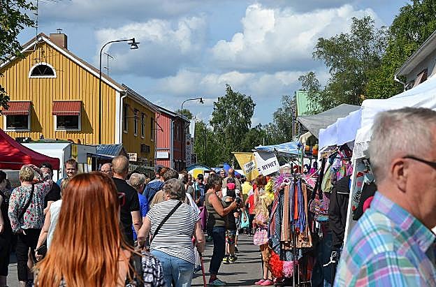 Paseantes caminan por una calle de Överkalix en un día estival de mercado.