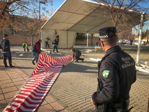 Un agente de la Policía Local observa el desmantelamiento de la gran carpa ubicada sin permiso alguno en el barrio de Cartuja. 