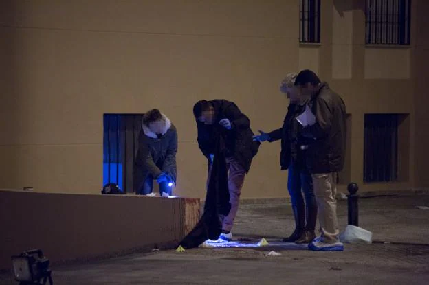 Agentes de la Policía Nacional inspeccionan ropa y restos de sangre de la víctima.