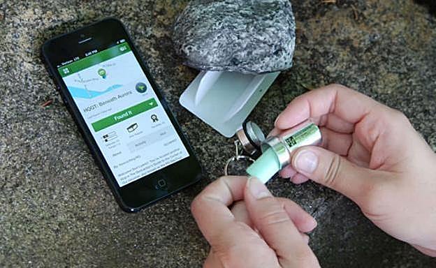 Una joven abre un de los paquetes escondidos guiada con la app de su móvil.