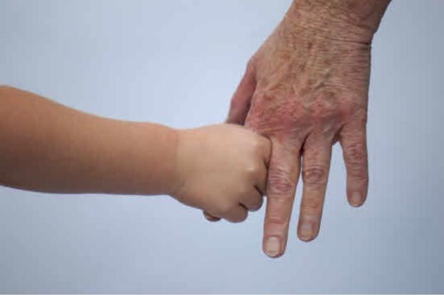 Un nieto agarra del dedo la mano de su abuela. 