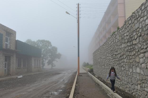 Una niña armenia camina bajo una densa niebla por una calle de Shushí.