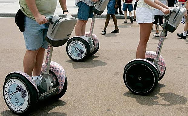Varias personas montan un patinete eléctrico. 
