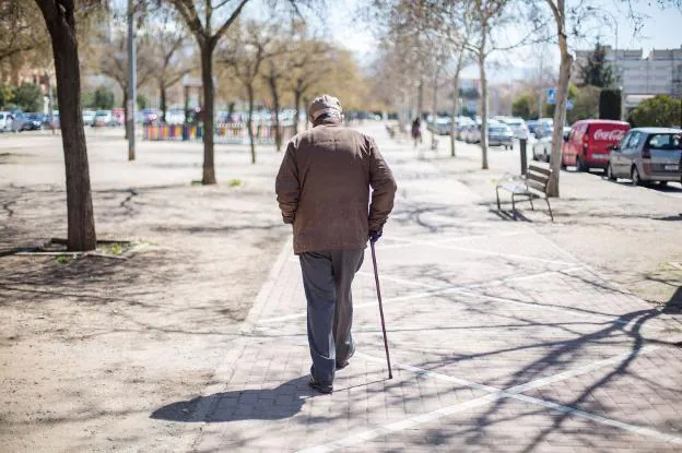 Un anciano camina al sol. 