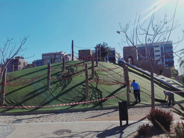 Dos operarios de la empresa reparan el césped de esta atracción del Parque de las Familias de la capital almeriense. 