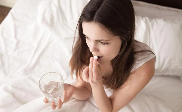 Una mujer toma una pastilla antes de irse a dormir 