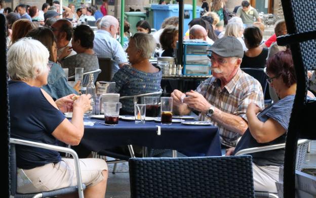 Varios turistas toman refrescos y bebidas en una terraza de un local de hostelería.