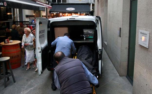 El cuerpo de la mujer es introducido en una furgoneta de los servicios funerarios.