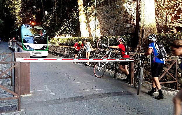 Ciclistas pasan sus vehículos por un acceso peatonal.