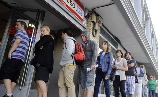 Varias personas esperando a las puertas de la oficina de empleo.