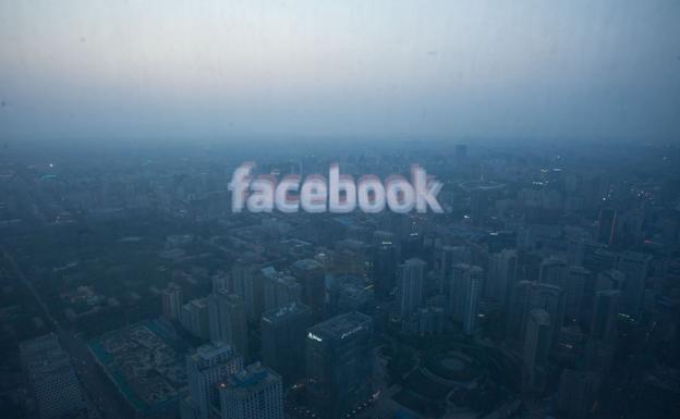 El logotipo de Facebook se refleja en una ventanal desde el que se divisa una panorámica de Pekín.