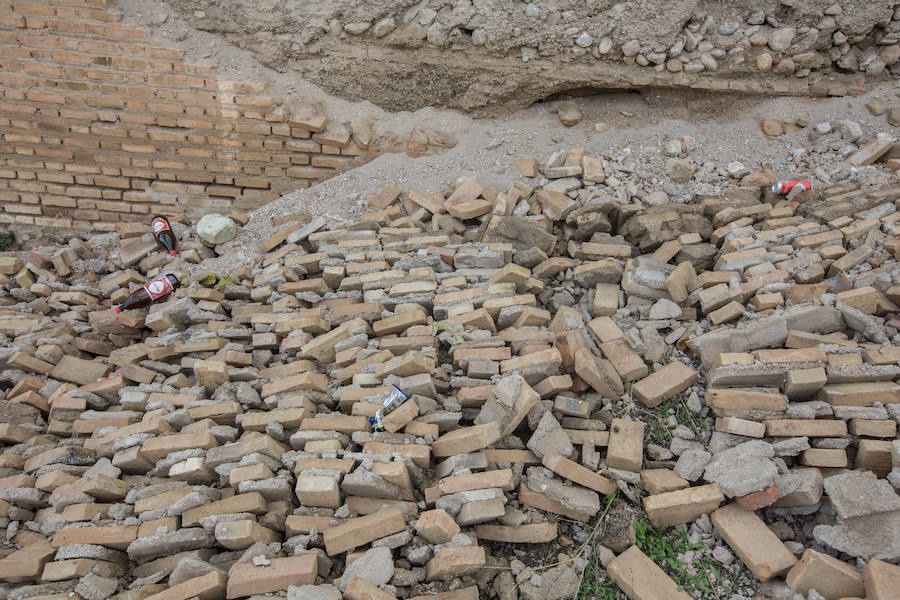 Cientos de ladrillos de lo que prodría ser el revestimiento de la muralla están amontonados junto a restos de basura