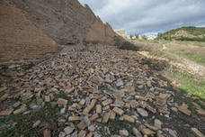 Cientos de ladrillos de lo que prodría ser el revestimiento de la muralla están amontonados junto a restos de basura