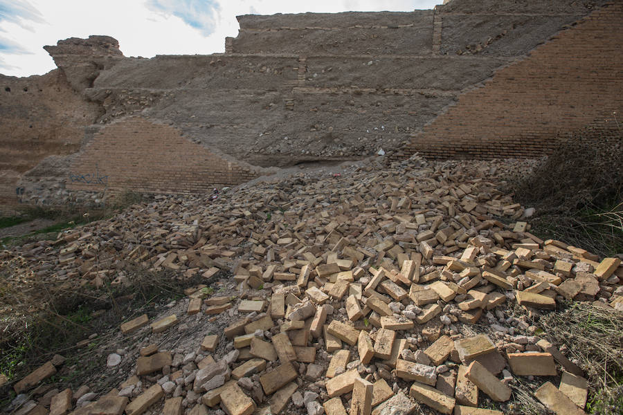 Cientos de ladrillos de lo que prodría ser el revestimiento de la muralla están amontonados junto a restos de basura