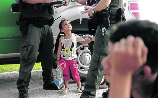 Una niña hondureña asiste a una conversación entre miembros de la patrulla fronteriza en un paso de Texas.