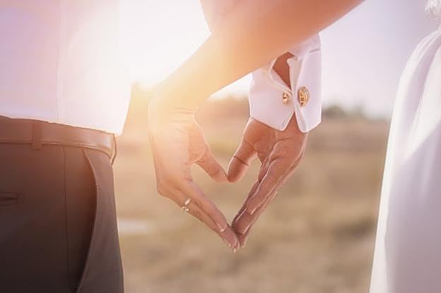 Fotografía de boda, con las manos de los contrayentes haciendo un corazón.
