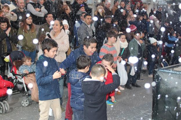 Niños disfrutan del efecto de nieve artificial al paso de la máquina.