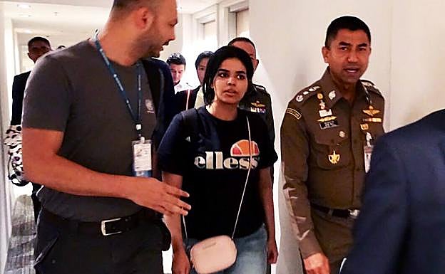 La mujer saudí Rahaf Mohammed al-Qanun (C) es escoltada por un oficial de inmigración (D) de Tailandia y funcionarios del Alto Comisionado de las Naciones Unidas para los Refugiados (ACNUR) (I).