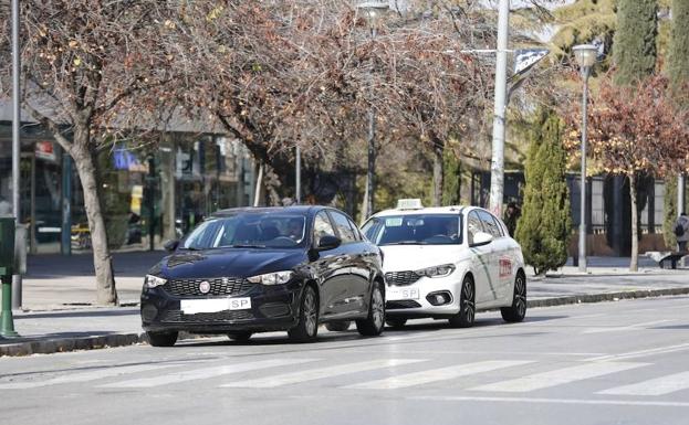 Un coche de Uber y un taxi, en la calle Arabial esta mañana