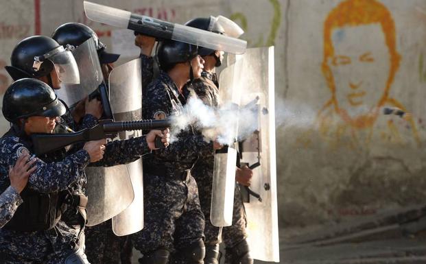 Antidisturbios hacen frente a manifestantes en un barrio de Caracas tras el levantamiento militar del lunes.