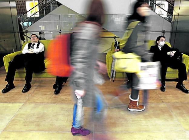 Dos trabajadores japoneses echan un sueñecito en un centro comercial de Tokio.