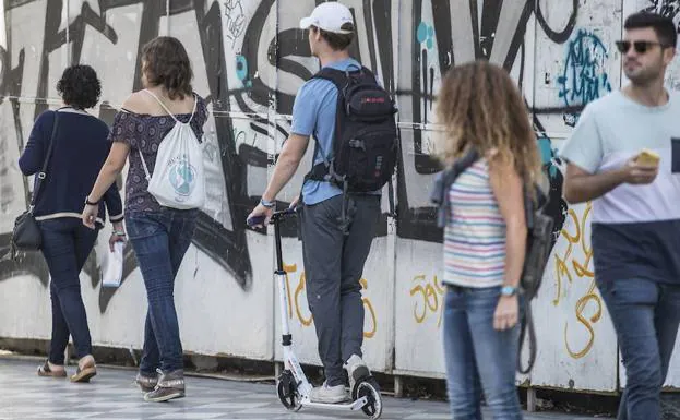 Un hombre circula con patinete eléctrico por una calle peatonal de Granada.