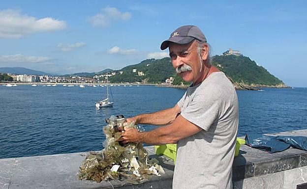 Un pescador recoge una montaña de plásticos extraídos del mar.