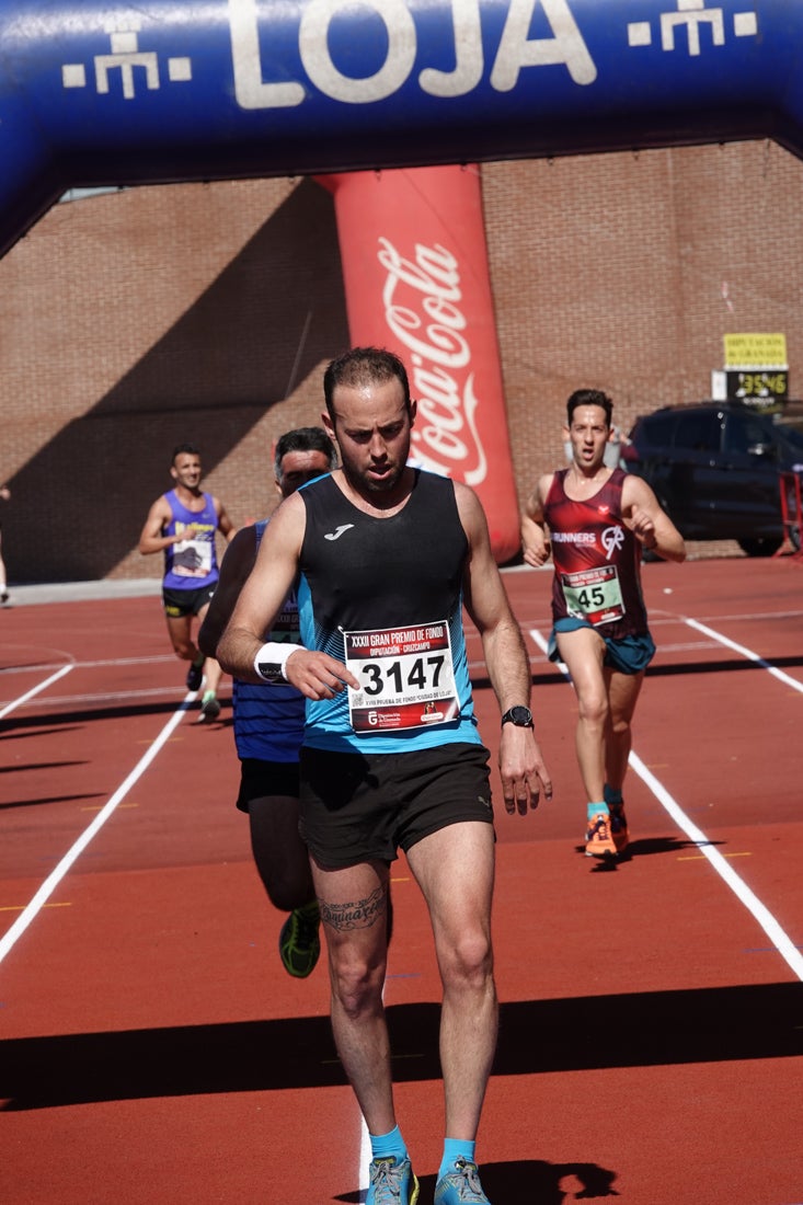 Manuel Santiago entra vistorioso a meta en la prueba de fondo de Loja. También lo hace victoriosa la más veterana de la cita. Y cientos de corredores desilan camino de la llegada al tartán.