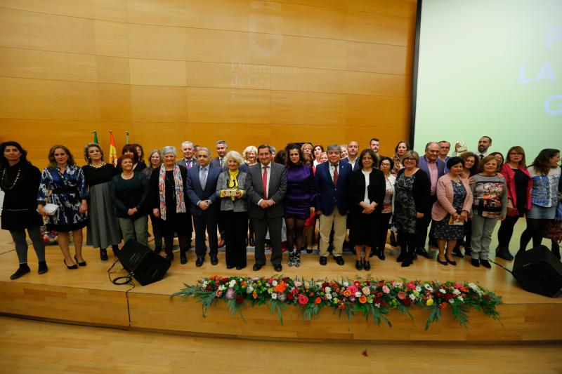 Premiadas y premiados por la Diputación posan en el escenario junto a representantes institucionales.