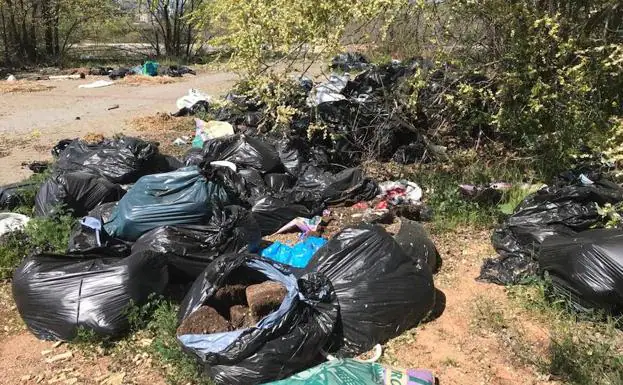 Maceteros y restos de tierra se acumulan en el solar situado junto a una gasolinera del barrio granadino de Almanjáyar.