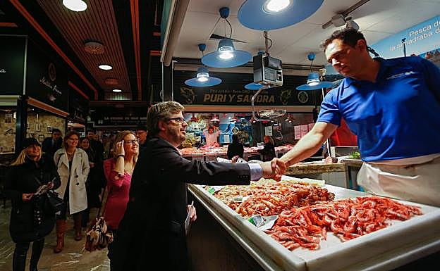 Fran Hervías estrecha la mano de uno de los responsables de los puestos del Mercado de San Agustín.
