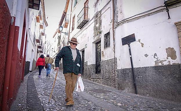 Un vecino camina sobre uno de los empedrados históricos del Albaicín