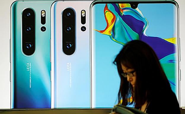Una mujer pasa delante de un cartel de publicidad de Huawei