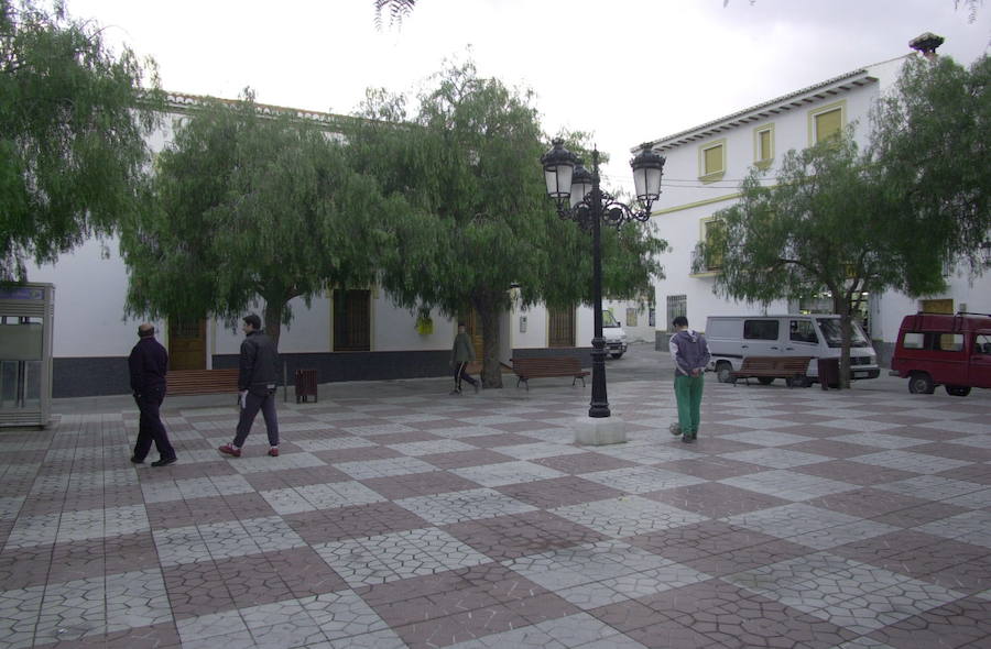 Tres personas pasean por la plaza principal de Gualchos