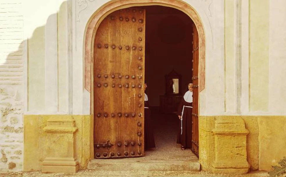 Dos monjas de Santa Isabel la Real entreabren la puerta principal del monasterio.
