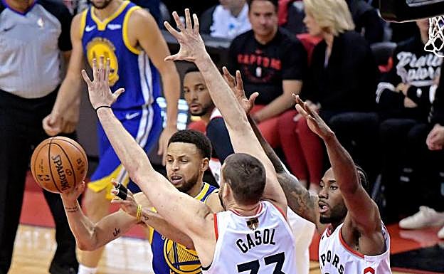 Marc Gasol (i) y Kawhi Leonard (d) defienden una penetración a canasta de Stephen Curry.