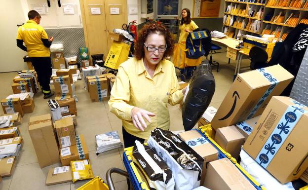 Una trabajadora de Correos procesa varios paquetes en una oficina postal. 