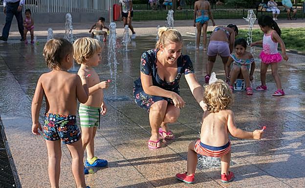 Varios niños se refrescan en el agua de la fuente de la Plaza de la Hípica del Zaidín. 