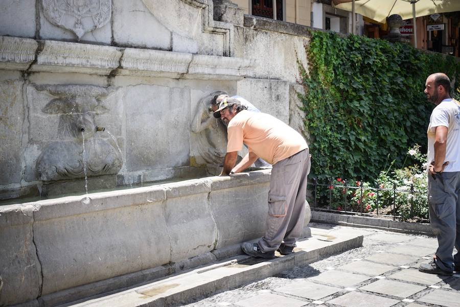 Granadinos y visitantes se las apañan en las calles para no sufrir mucho el enorme calor de estos días