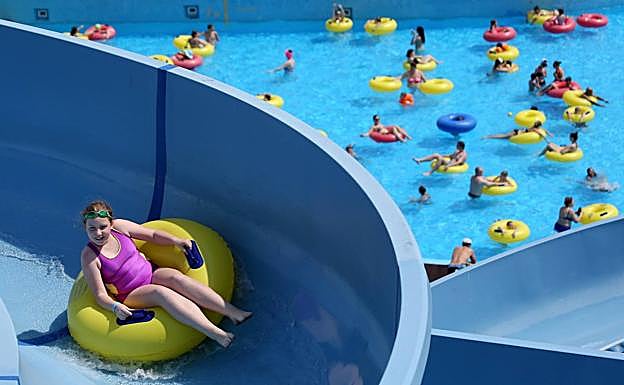 Una niña se desliza con un flotador por un tobogán