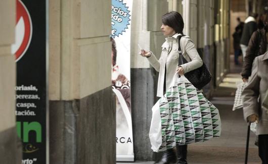 Una mujer de compras con una bolsa de plástico de El Corte Inglés.