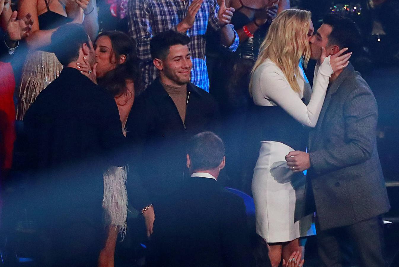 Los Jonas Brothers besan a sus respectivas mujeres.
