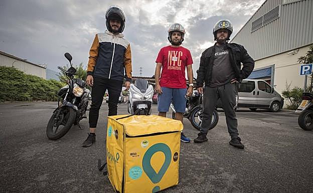 Ricardo, Víctor y Alejandro posan con sus motos y una mochila de Glovo para IDEAL.