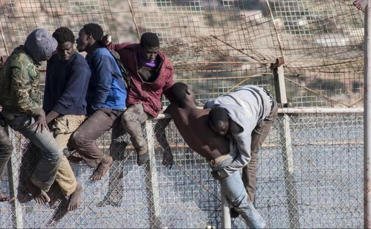 Inmigrantes subidos a la valla, en una imagen de archivo.