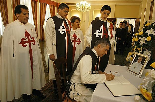 Miembros del movimiento Heraldos del Evangelio firman en un libro de honor ante una imagen de Juan Pablo II, su valedor.