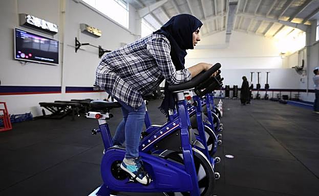 Rabia Behkam, de 24 años y entrenadora en uno de los nuevos gimnasios, pedalea sobre una bici.
